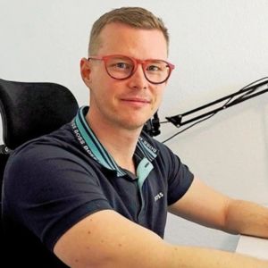 René Mayer, junger Mann mit Brille beim Sprechen ins Mikrofon