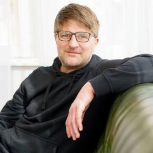 Andreas Reinke, Mann mit Brille auf grünem Sessel sitzend