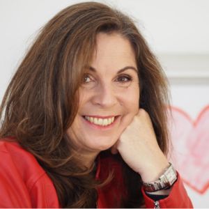 Ines Berger, Frau mit braunem Haar im roten Oberteil, Hand am Gesicht