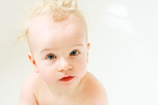 Portrait eines blonden Babys mit großen Augen auf hellem Hintergrund