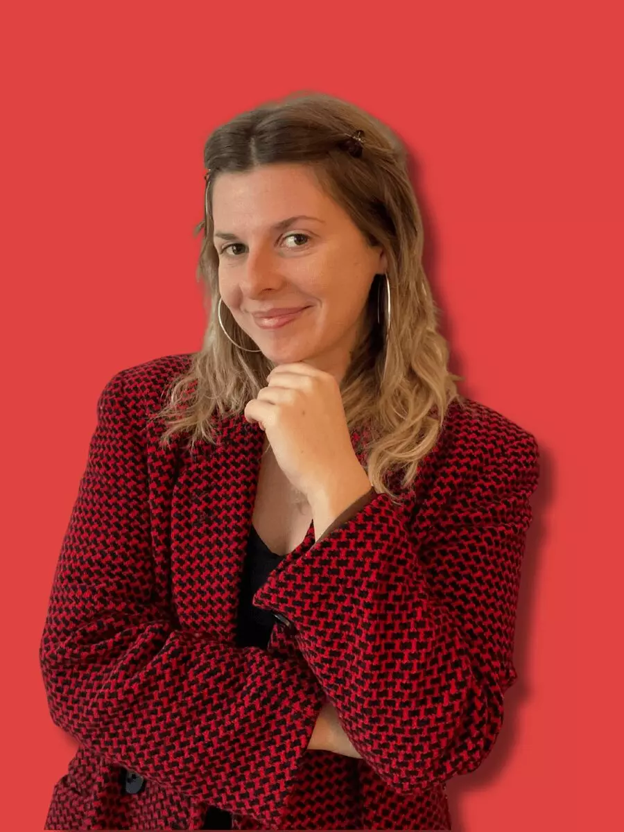 Frau mit braunen Haaren in rotem Blazer, Hand am Kinn, nachdenkliche Pose
