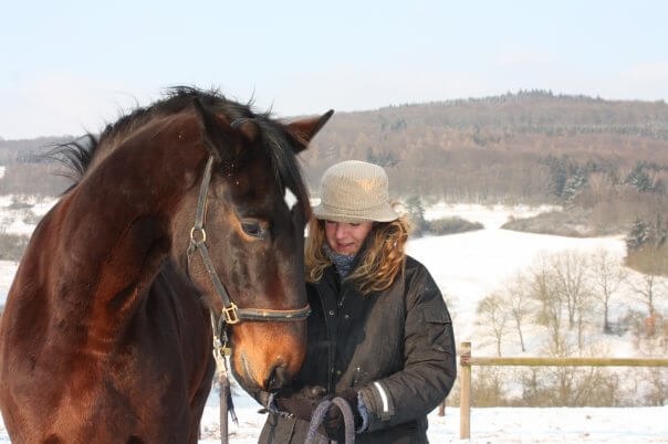 Daniela Vögele mit braunem Pferd Schnee, Hut, Winterporträt