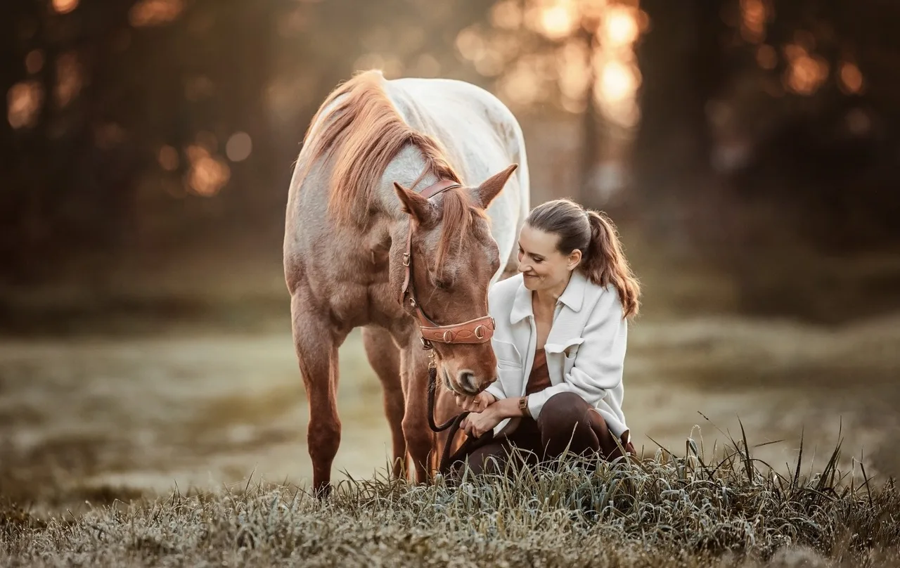 Petra Haubner mit braunem Pony, weiße Kleidung, Pferdetrainerin