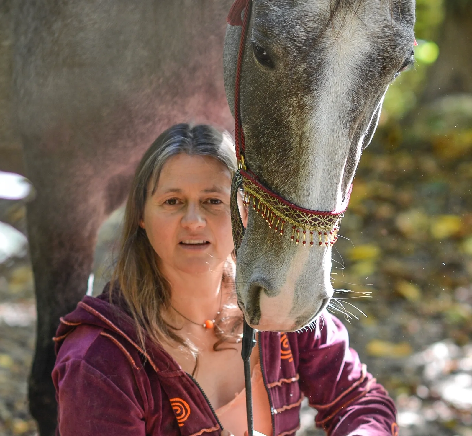 Antoinette Hitzinger in weinroter Jacke mit Pferd, Pferdekopf mit verziertem Halfter