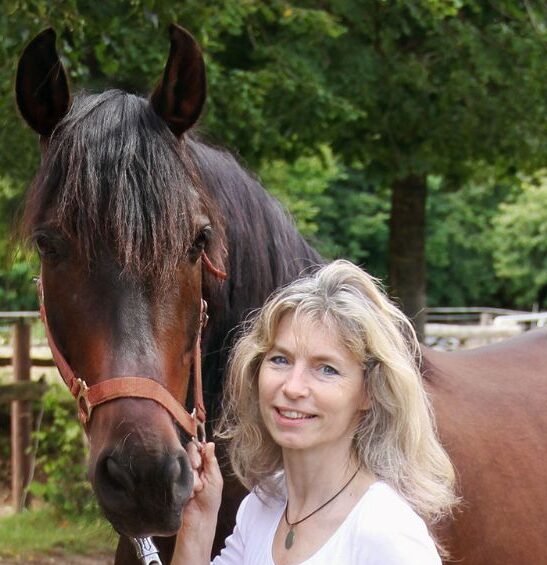 Martina Kiss mit dunklem Pferd, Porträt, Pferdetrainerin