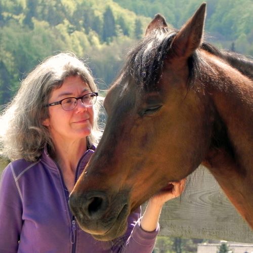 Bettina Loeber mit Pferd, lila Shirt, Brille, Pferdetrainerin