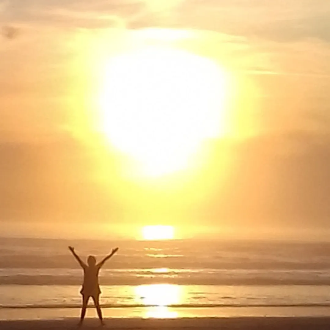 Körperaufrichtung – Energie-Coaching per Zoom 12 Person mit erhobenen Armen vor Sonnenaufgang am Strand