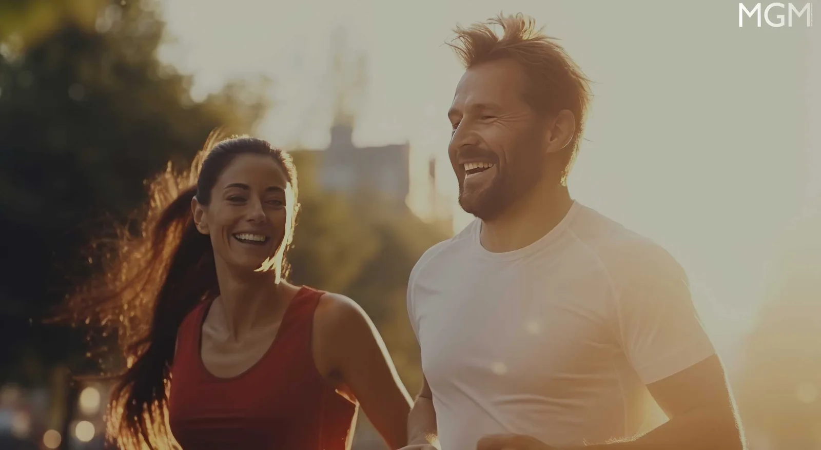 Zwei Läufer in Sportkleidung laufen gemeinsam bei Sonnenaufgang in urbanem Umfeld, wirken glücklich und motiviert