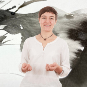 Ramona Weyde, Sprecherin mit braunen Haaren in weißem Shirt vor abstraktem grauem Hintergrund
