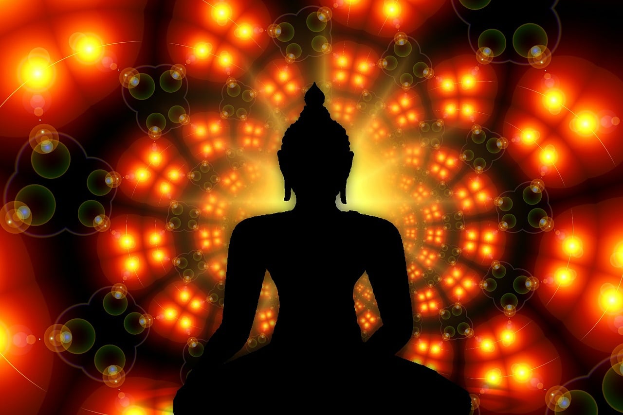 Silhouette einer Person in Meditationshaltung vor leuchtendem gelbem und orangem Energiehintergrund