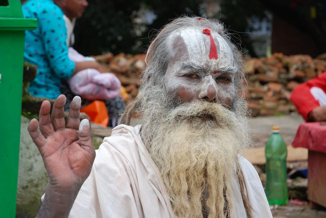 Indischer Sadhu mit langem weißem Bart, weißer Gesichtsbemalung und rotem Tilaka