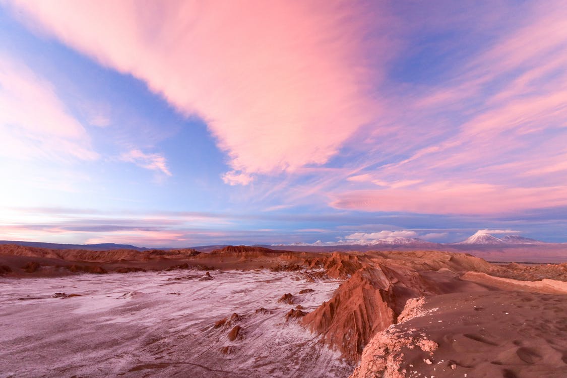 Landschaftsfotografie: Rosa-orange Sonnenuntergang über Wüstenebene mit Gebirge im Hintergrund, inspirierende Naturszene