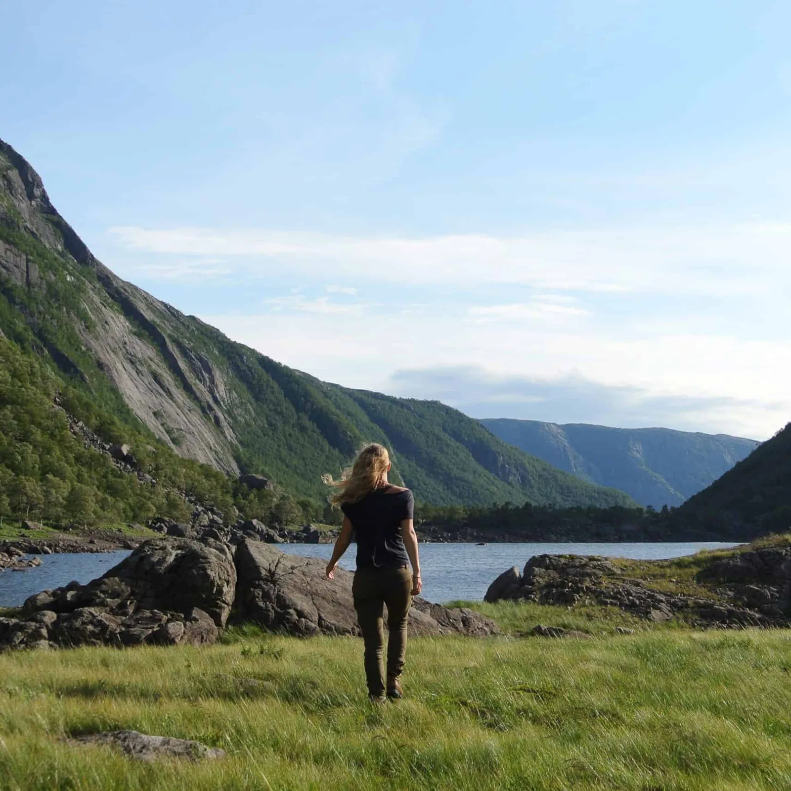 Frau von hinten in Landschaftsszenerie mit See, Bergen und Wald im Hintergrund