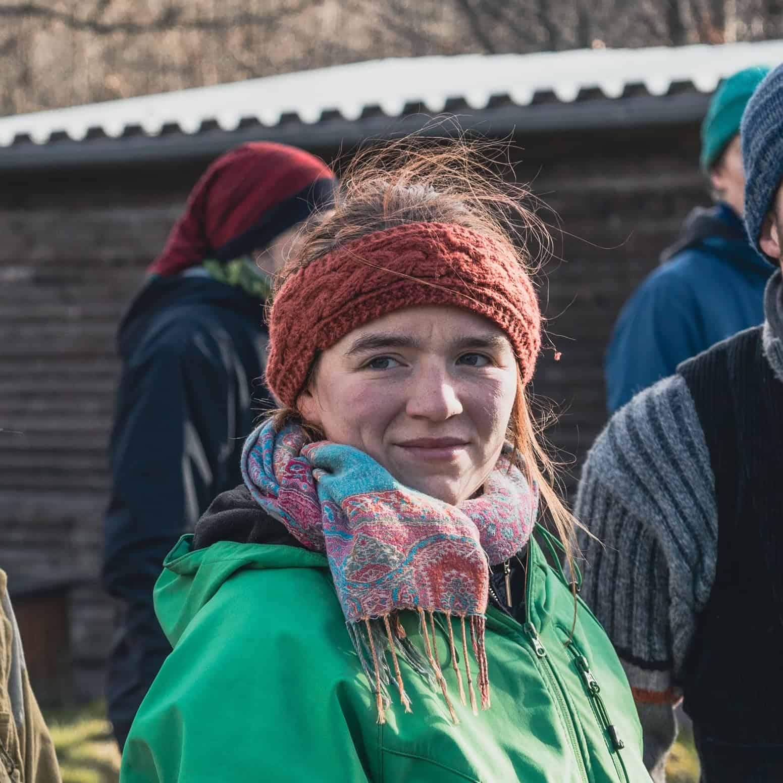 Junge Frau mit roter Mütze und grüner Jacke, karierter Schal