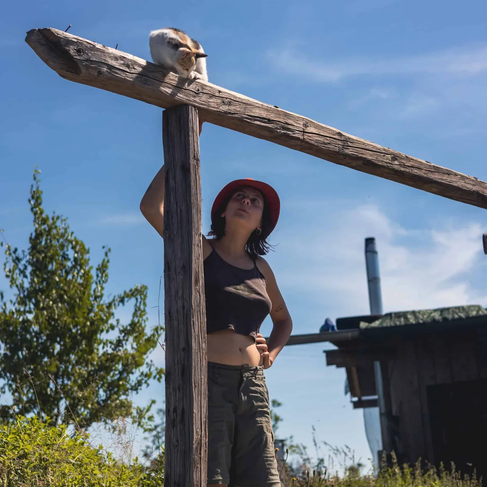 Porträt einer Frau mit rotem Hut unter Holzbalken vor blauem Himmel