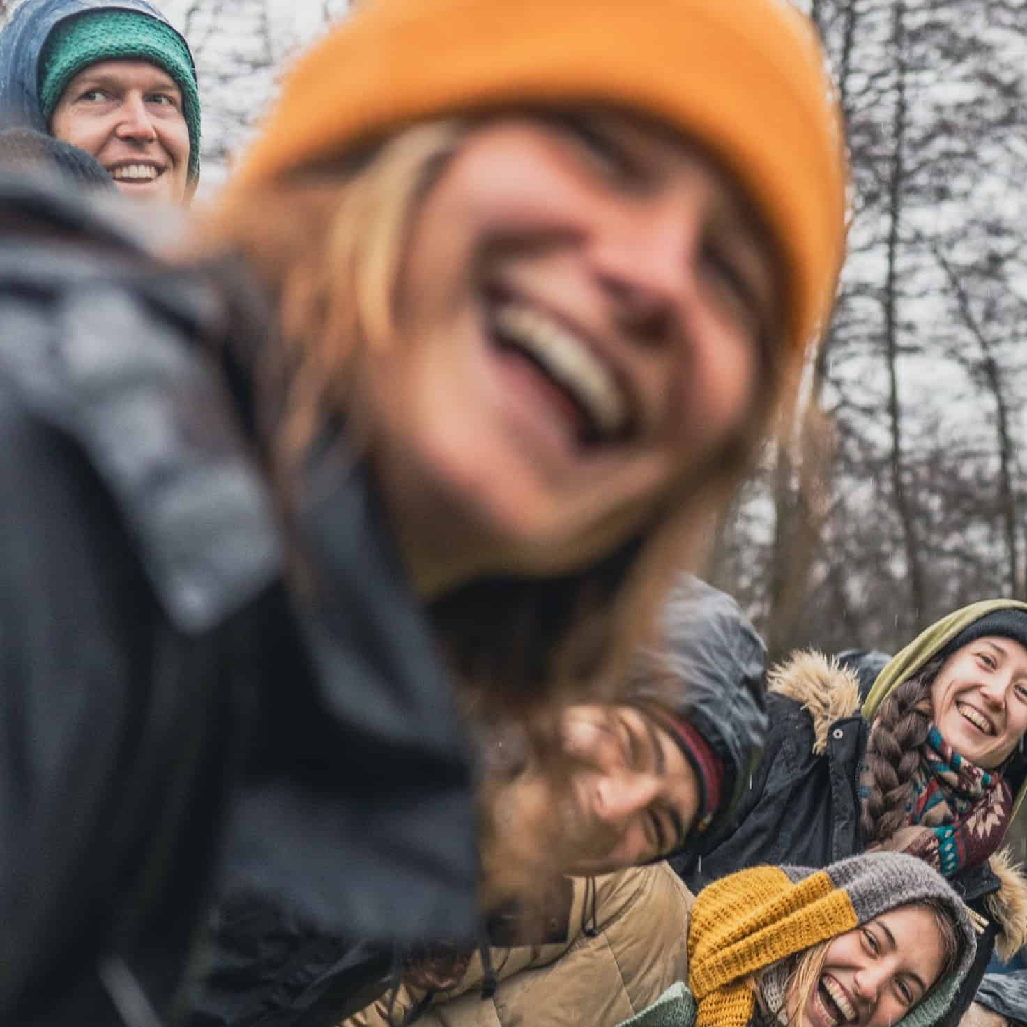 Porträt einer lächelnden Frau mit grünem Stirnband und blauem Hut in winterlicher Kleidung im Freien
