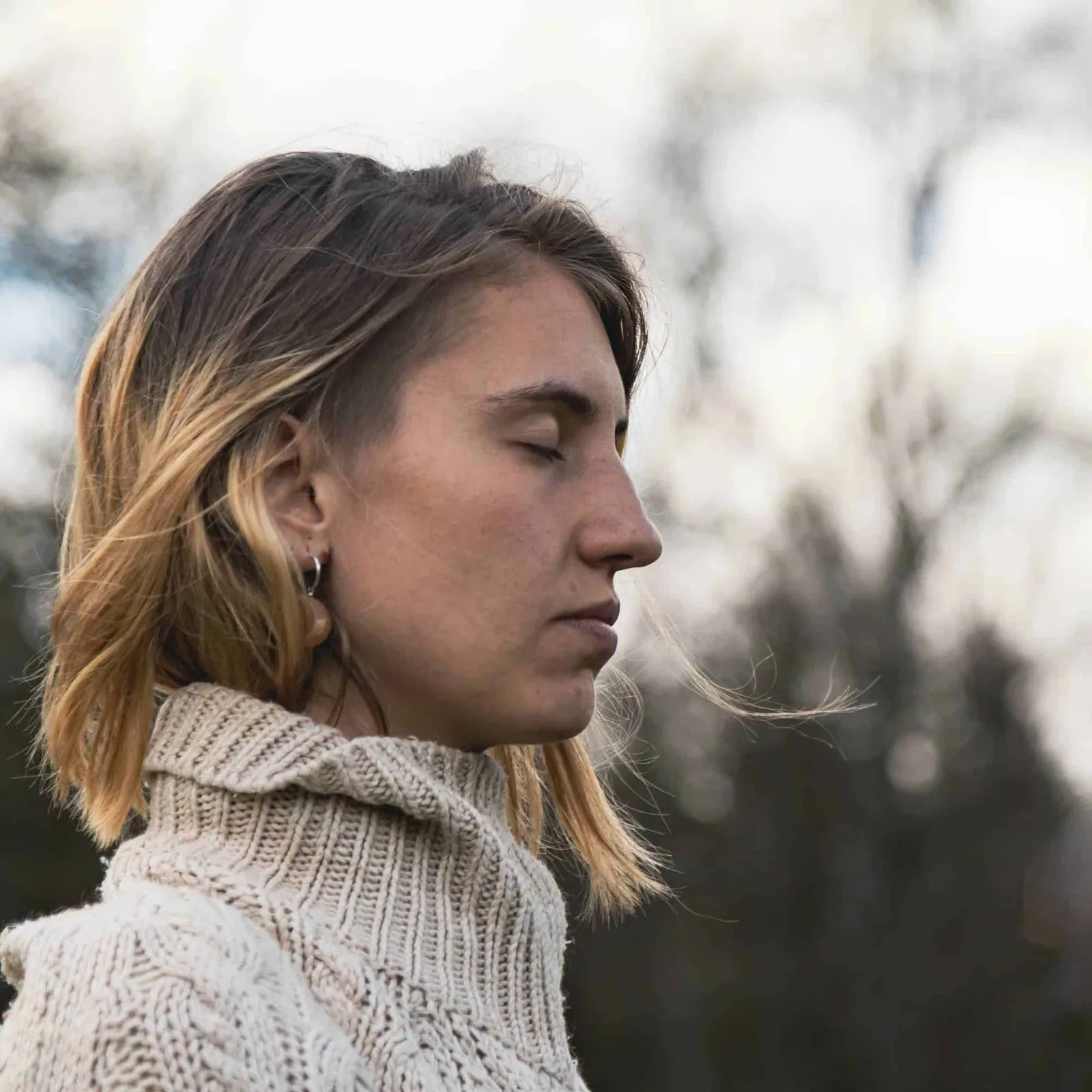 Frau mit hellbraunen Haaren im Seitenprofil mit Strickpullover