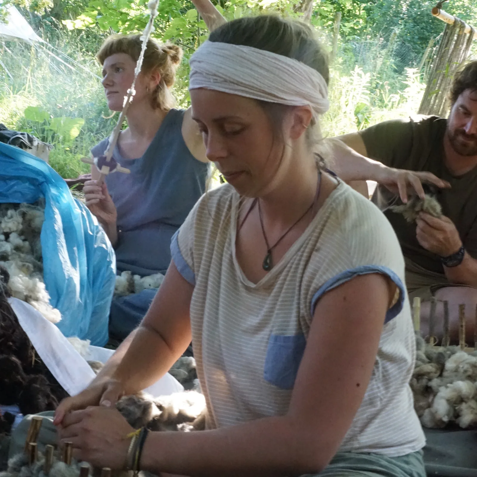 Frau mit Stirnband beim Arbeiten an Naturmaterialien in einer Gruppe im Freien