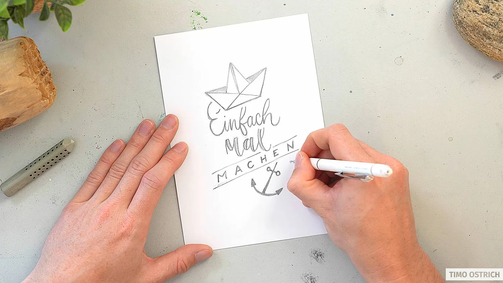Hände zeichnen handschriftlich Texte mit Lettering-Stil auf weißem Papier mit Werkzeugen