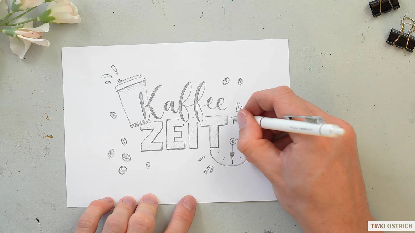 Skizze 'Kaffeezeit' mit Kaffeetasse auf weißem Papier vor unscharfem warmem Hintergrund