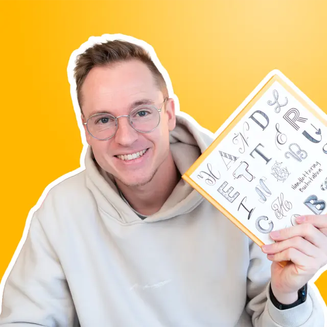 Porträt von Timo Ostrich mit Brille, weißem Hoodie vor gelbem Hintergrund, hält Skizzenblock