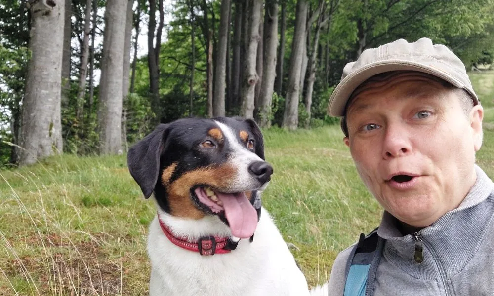 Mann mit Cap neben Hund im Wald, Porträtfoto im Freien