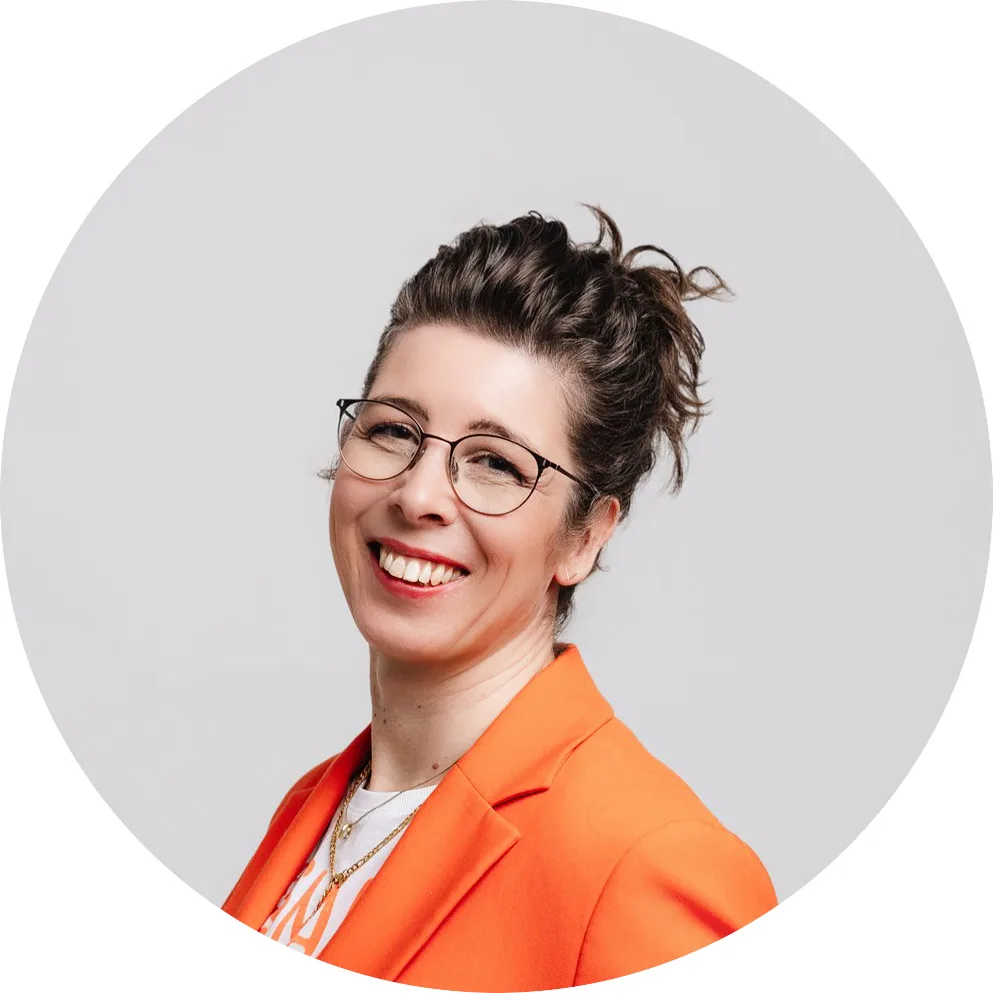 Porträt von Dominique Wagner, Lichtplanerin, mit Brille und orange-rotem Blazer