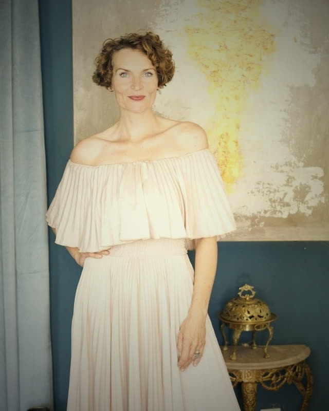 Stefanie Bruns in cremefarbenem Schulterfreiem Kleid mit abstraktem Kunstwerk im Hintergrund