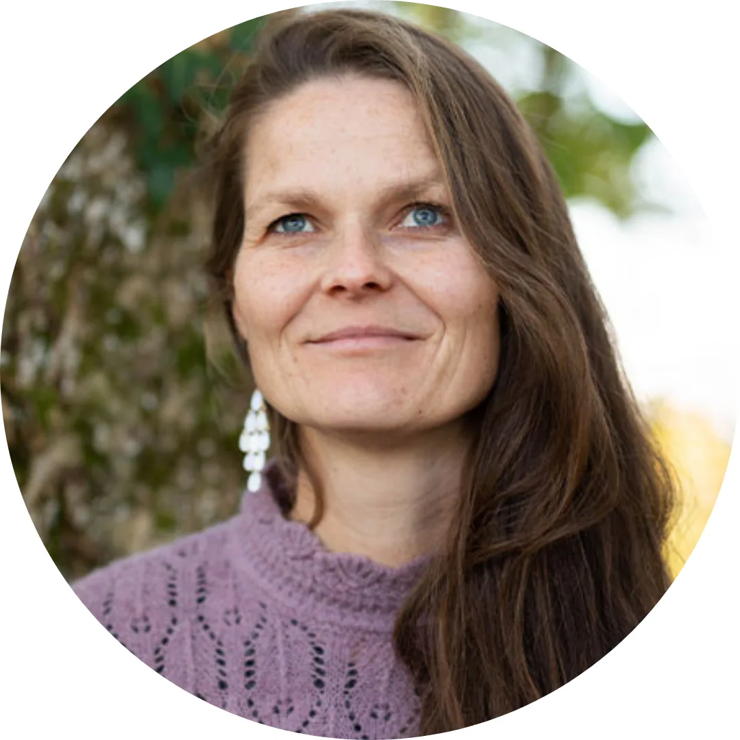 Salomea Klaus Portrait – Frau mit braunem Haar in lila Pullover vor grünem Naturhintergrund