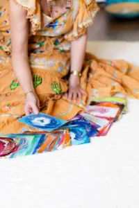 Hände ordnen mehrere bunte Energiebilder mit Spiralen und Mustern auf Stoff
