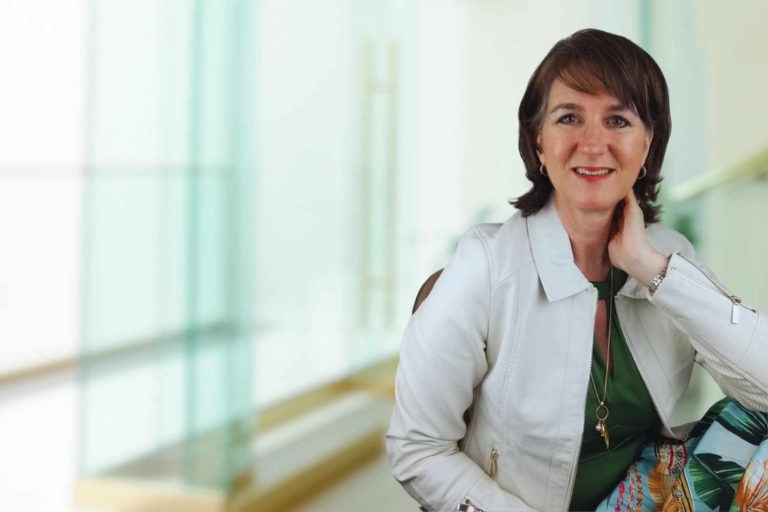 Tanja Meltsch im weißen Blazer vor modernem Büro-Hintergrund lächelnd