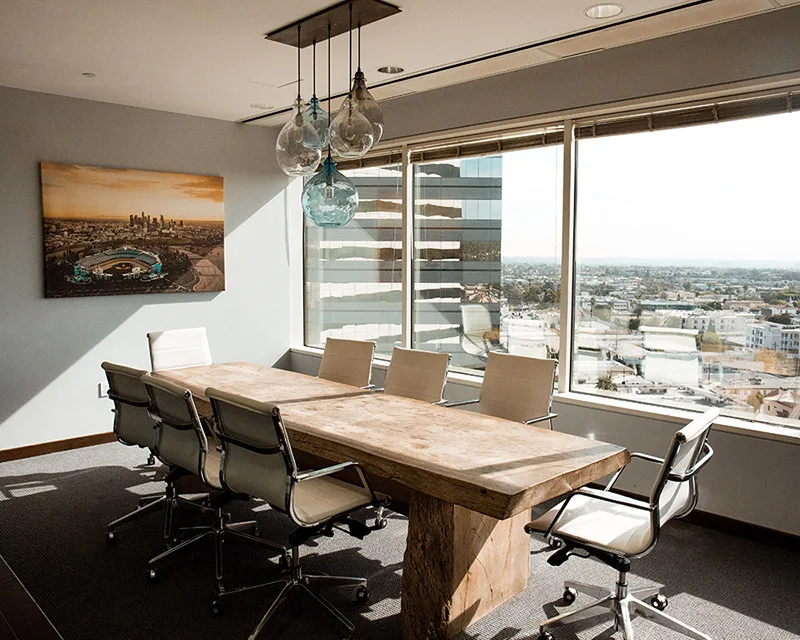 Modernes Büro mit Konferenztisch aus Holz, Glaswänden und Stadtblick