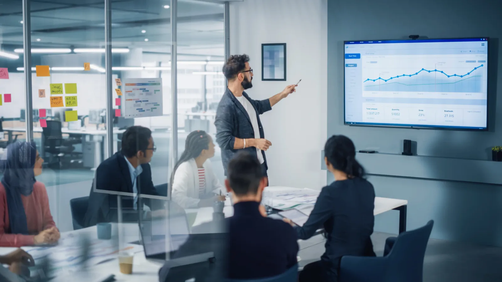 Präsentation in modernem Büro, Mann erklärt Analytics-Dashboard auf Monitor