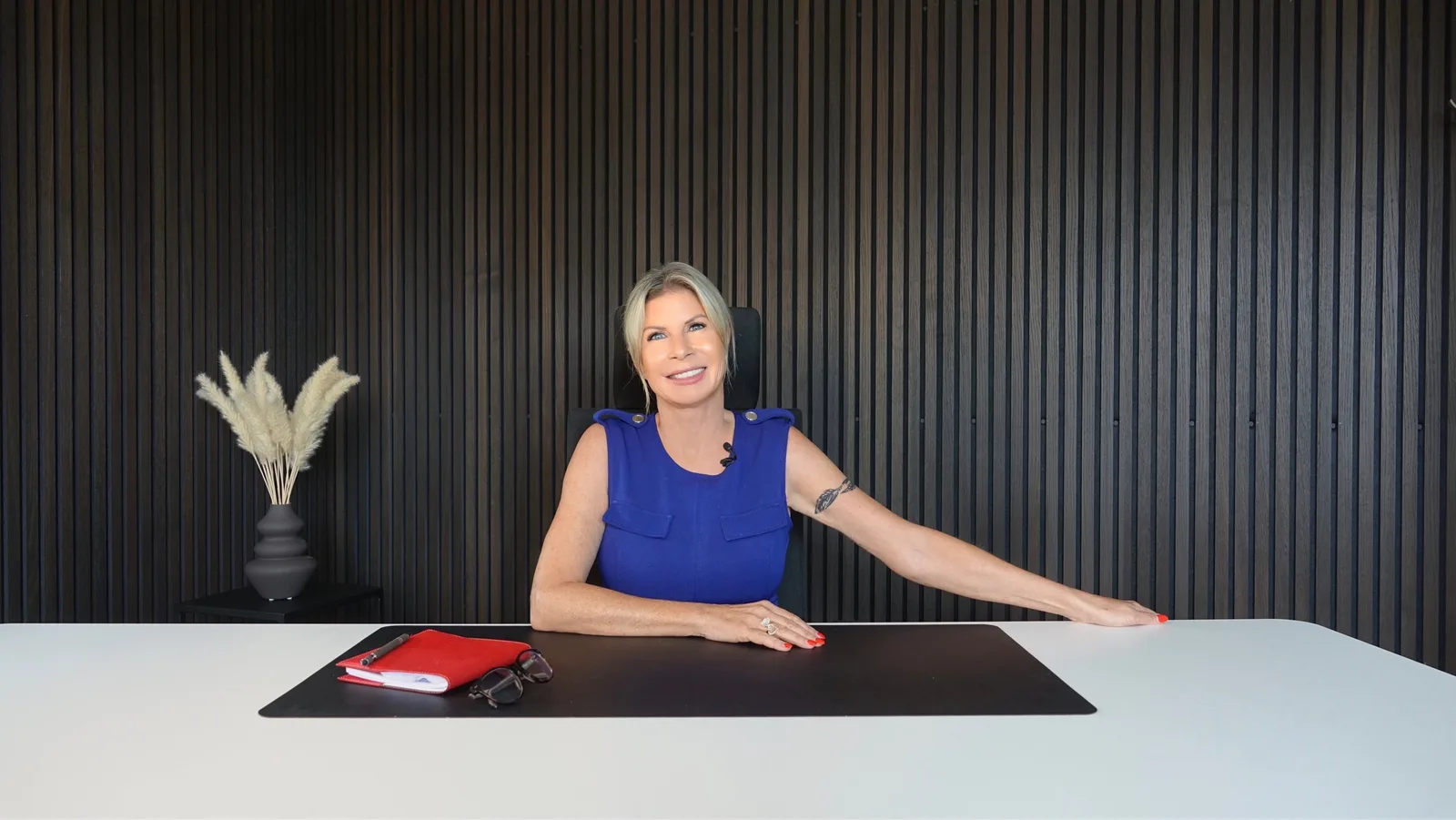 Stefanie Brings sitzt am Schreibtisch im professionellen Setting mit Trockenbürstentopf