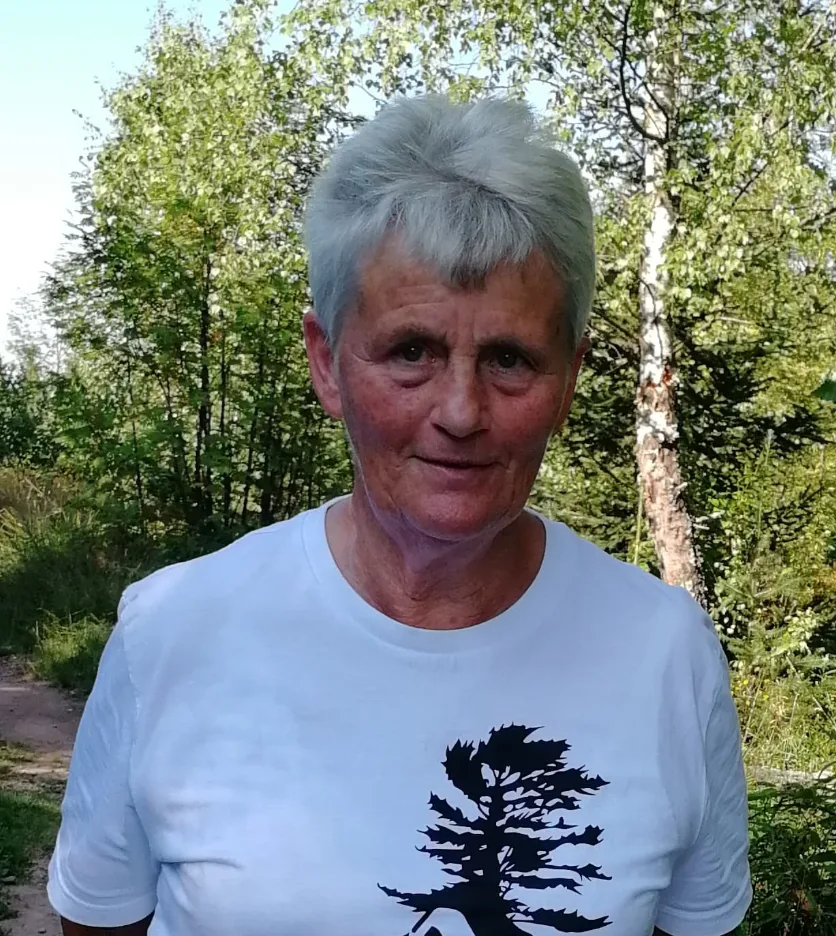 Doris Schwär – älterer Mann mit grauem Haar, weißes T-Shirt mit Baum-Motiv, Birkenwald-Hintergrund