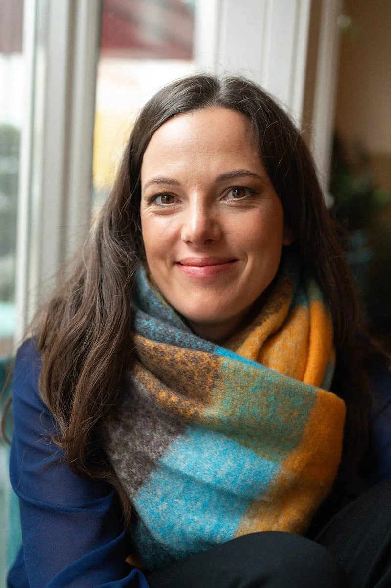 Dr. Martina Wengenroth Porträt mit farbigem Tuch vor Fenster, freundlicher Gesichtsausdruck
