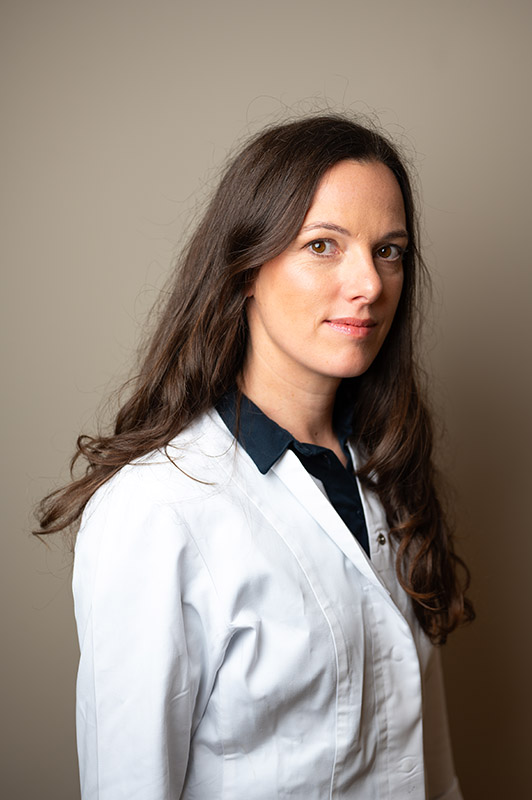 Dr. Martina Wengenroth Portrait im weißen Arztkittel vor grauem Hintergrund, seitlicher Blick