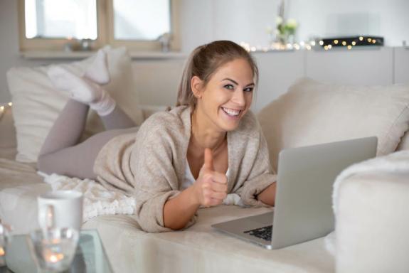 Medialität total – Videokurs zu Jenseitskontakten 6 Frau mit Laptop auf Bett lächelnd, helles Schlafzimmer mit Lichterkette