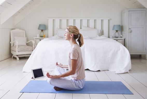 Medialität total – Videokurs zu Jenseitskontakten 7 Frau meditiert auf blauer Yogamatte im Schlafzimmer mit Tablet