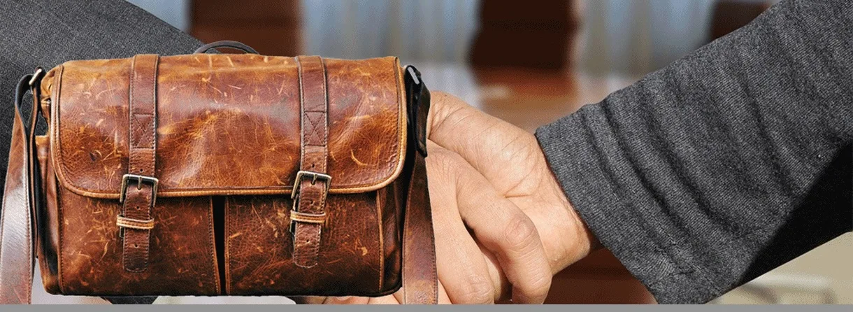 Hand hält braunen Lederkohler vor unscharfem Hintergrund