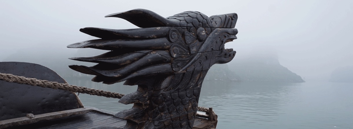 Schwarze Drachenstatue an Wasser mit Bergen im Hintergrund