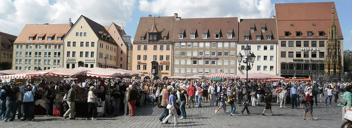 Marktplatz mit Marktständen und Besuchern vor historischen Gebäuden