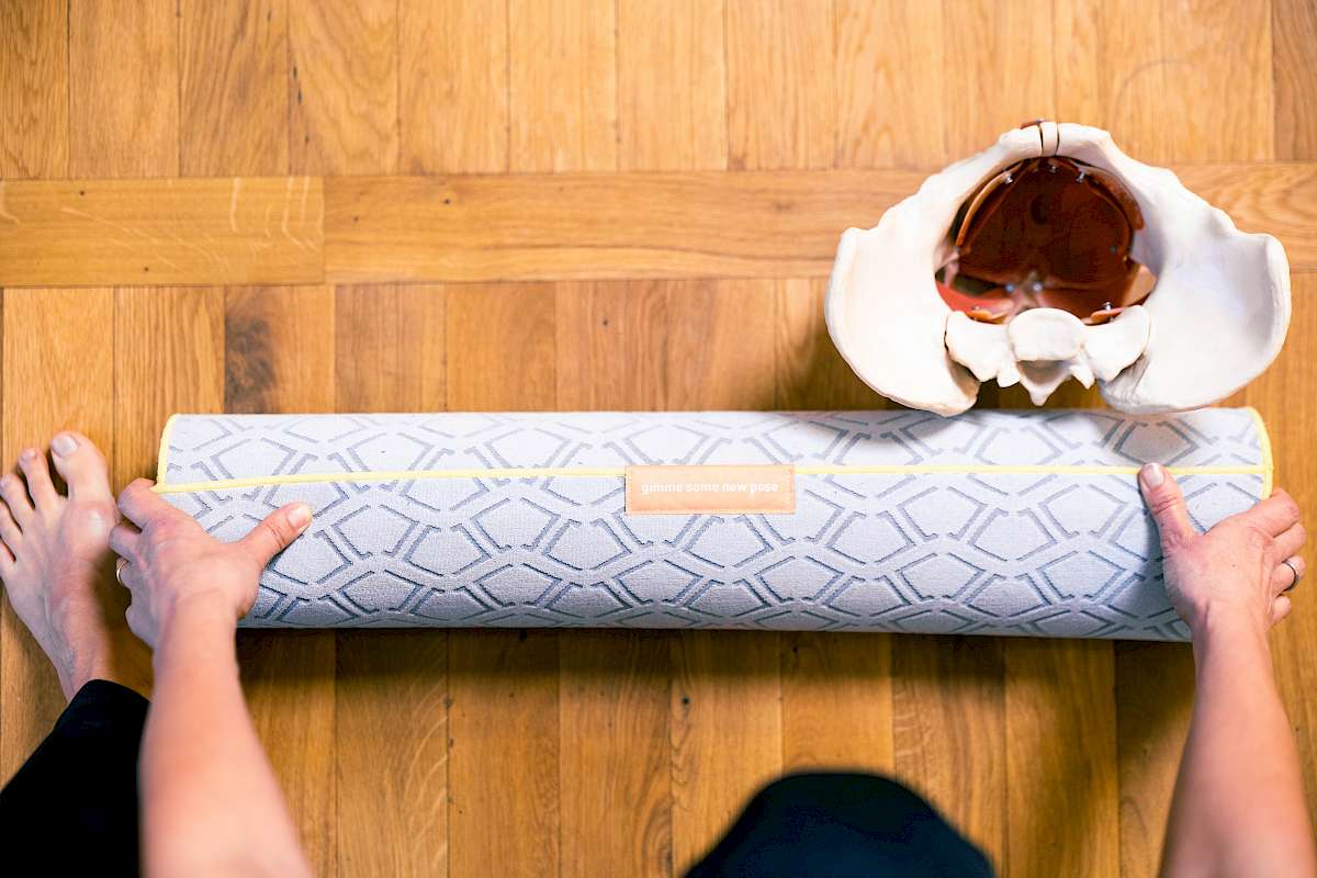 Mein Beckenbodenworkout – Starker Beckenboden Kraft 4 Overhead-Aufnahme von Händen auf Yoga-Matte mit Schale und Blumen auf Holzboden