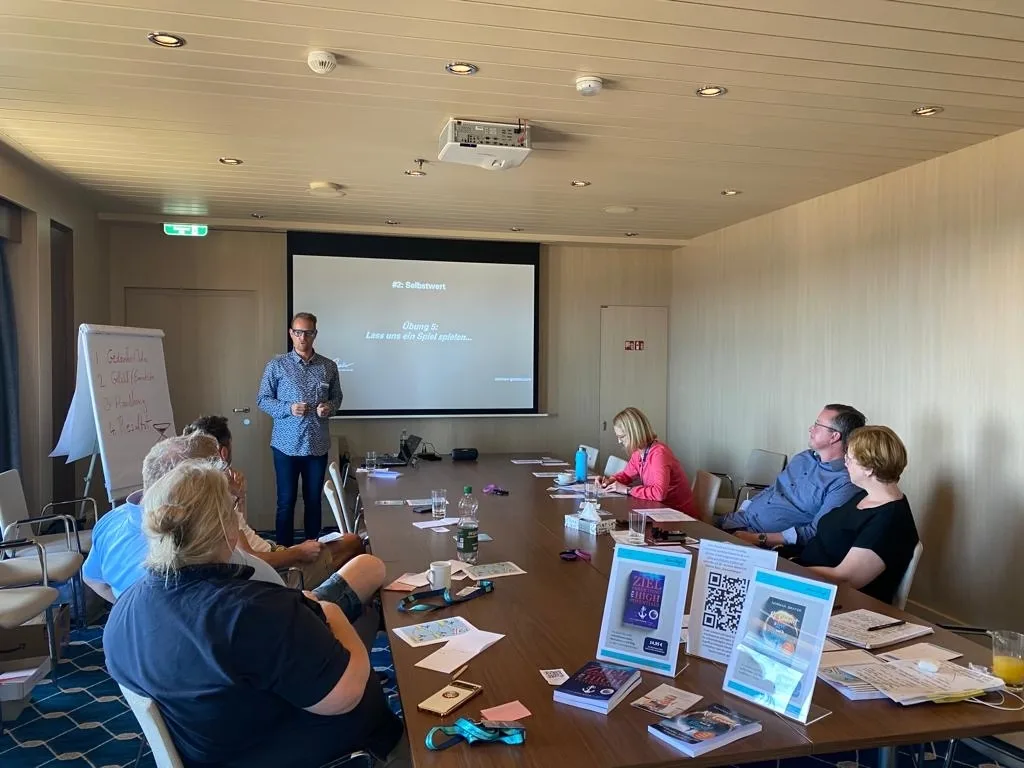 Norman Gräter präsentiert Workshop auf MeinSchiff vor Teilnehmern im Konferenzraum