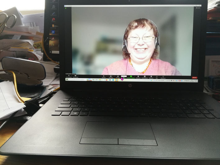 Videokonferenz-Screenshot auf Laptop-Bildschirm einer Person mit Brille