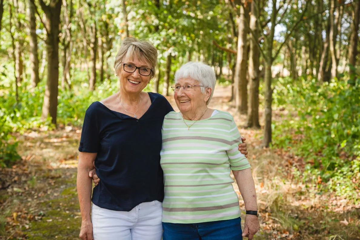 Zwei Frauen umarmt im Wald spaziergang, lächelnd, Trauer verarbeiten, Unterstützung