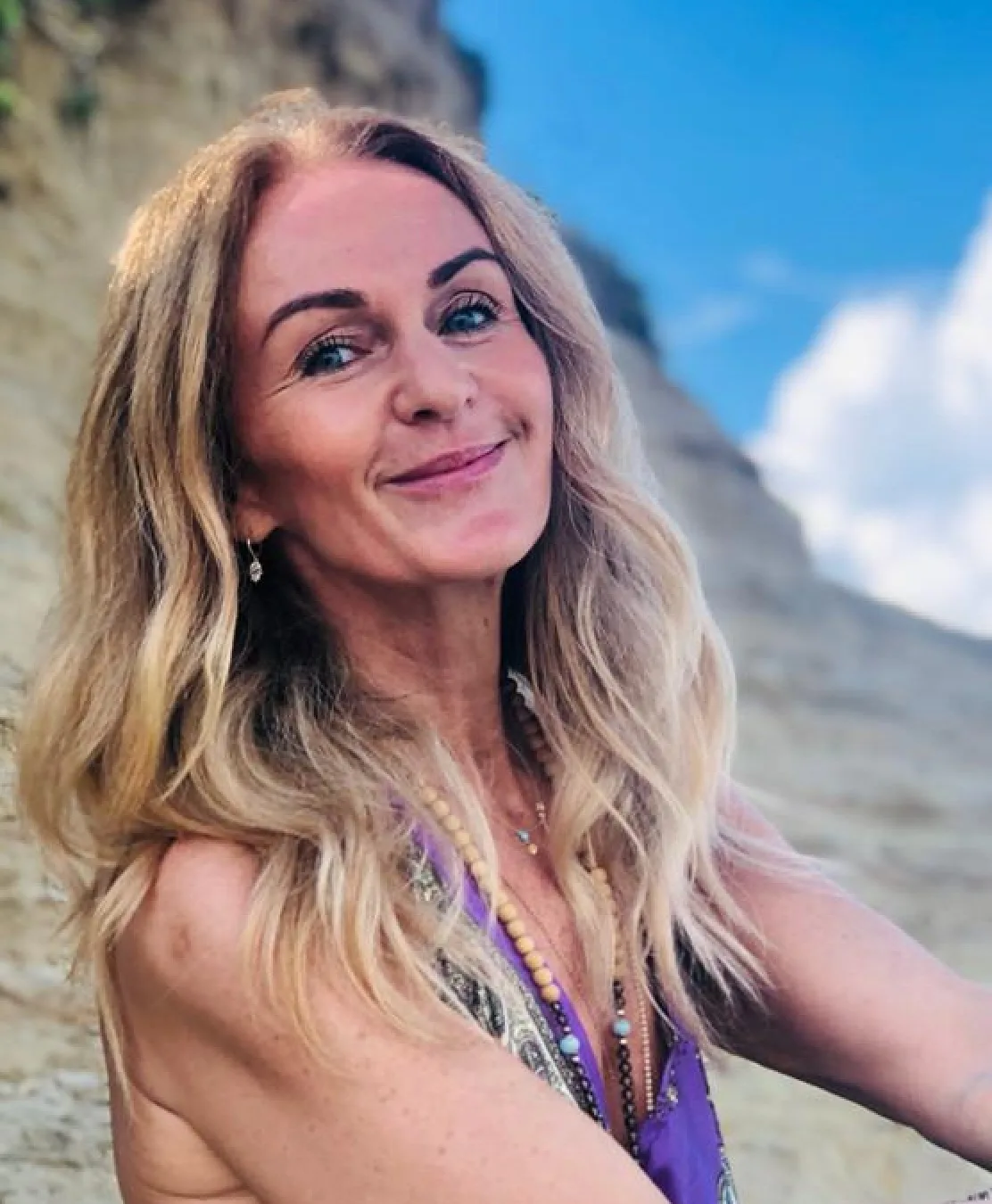 Frau mit blondem Haar am Berg vor Steinwand