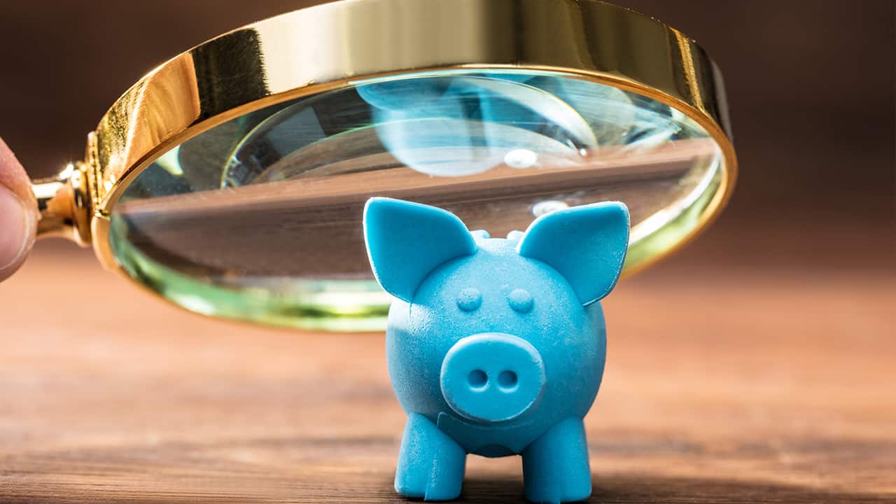 Blaues Sparschwein unter Lupe zeigt Analyse und Kontrolle von Finanzen