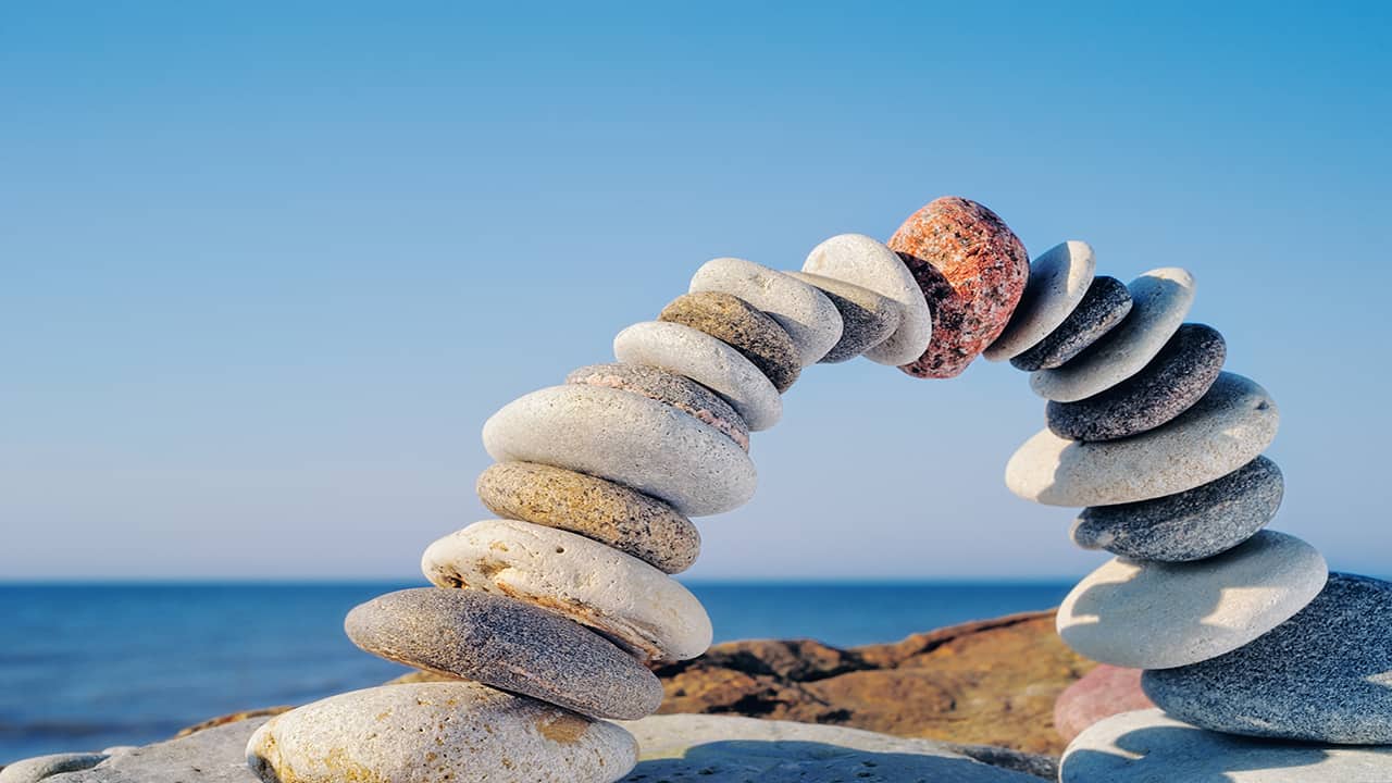 Steine in Bogenform am Strand symbolisieren Balance und Ausgeglichenheit