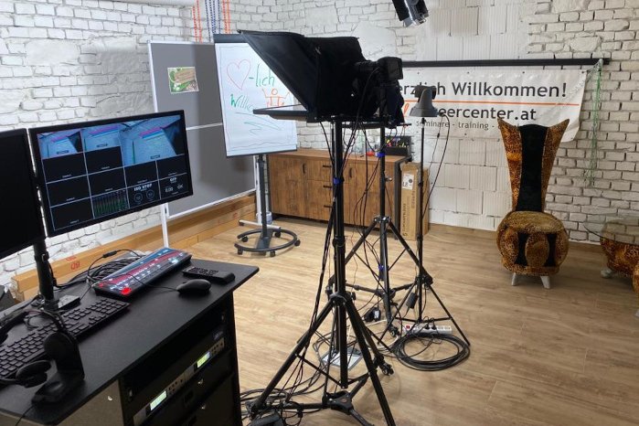 Videostudio mit Klavier, Monitoren und Willkommensschild in Backsteingebäude